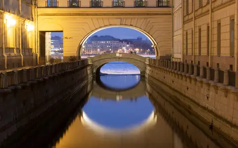 Beautiful view of a historic canal and bridge in Saint Petersburg at twilight, reflecting city lights