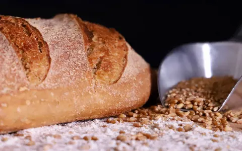A loaf of wholemeal bread with scattered wheat grains
