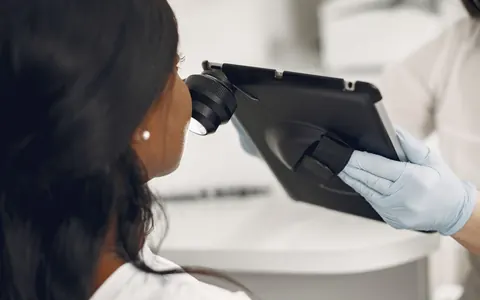 A dermatologist examining a patient's skin with a digital dermatoscope