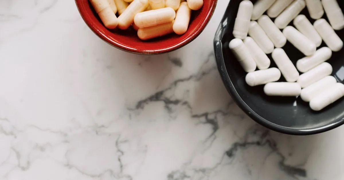 White capsules in a small bowl on a marble surface