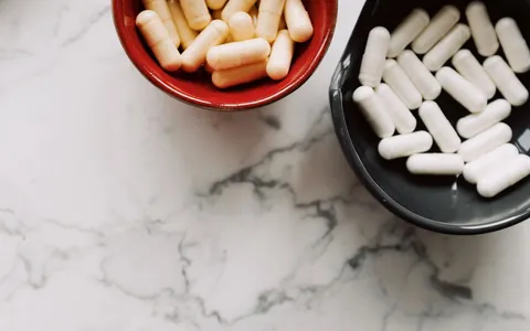 White capsules in a small bowl on a marble surface