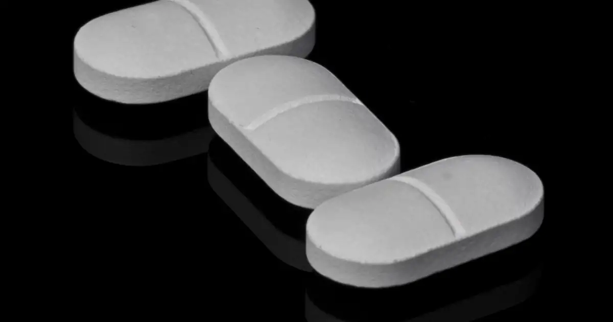 Three white tablets on a dark reflective surface