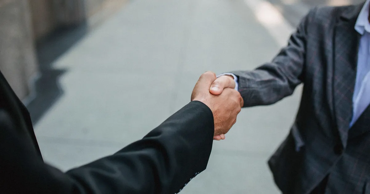 Two businesspeople shaking hands outdoors