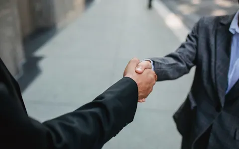 Two businesspeople shaking hands outdoors