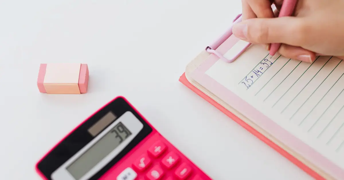 Close-up of hands using a calculator and writing equations on a notebook, perfect for math concepts