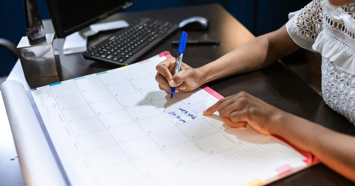 A person writing on a desk calendar