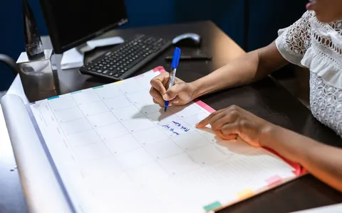 A person writing on a desk calendar