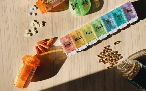 A colourful pill organizer with medication bottles on a wooden table