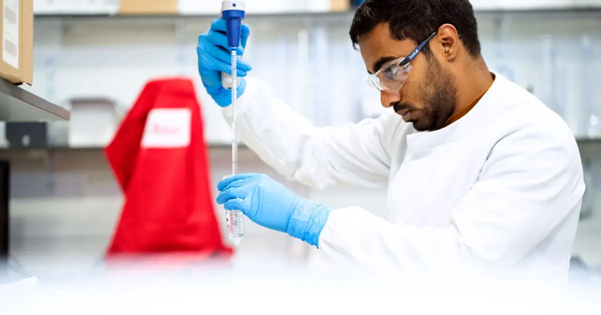 A focused scientist holding a pipette in a laboratory environment