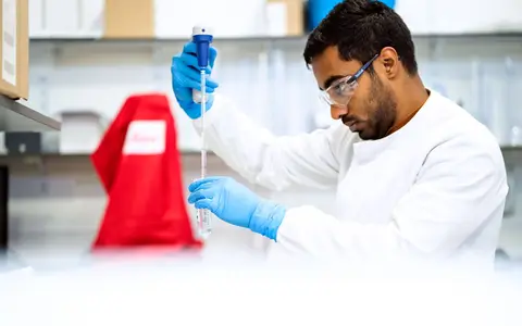 A focused scientist holding a pipette in a laboratory environment