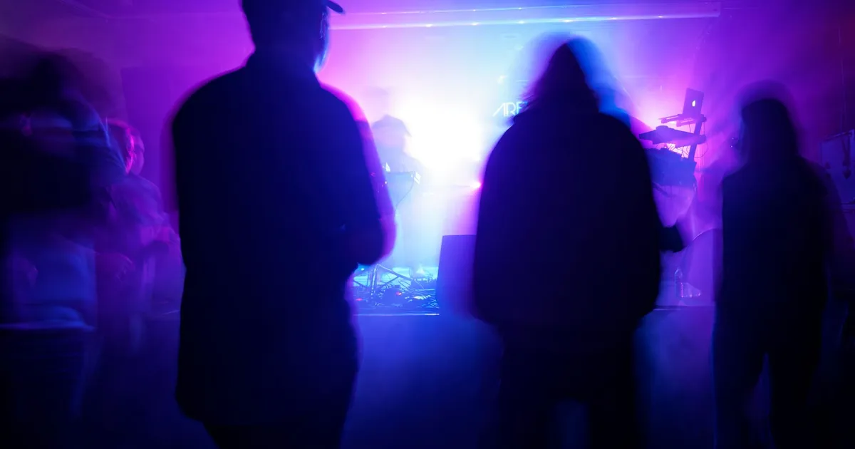 Silhouettes of a crowd under purple stage lights