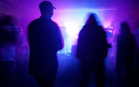 Silhouettes of a crowd under purple stage lights