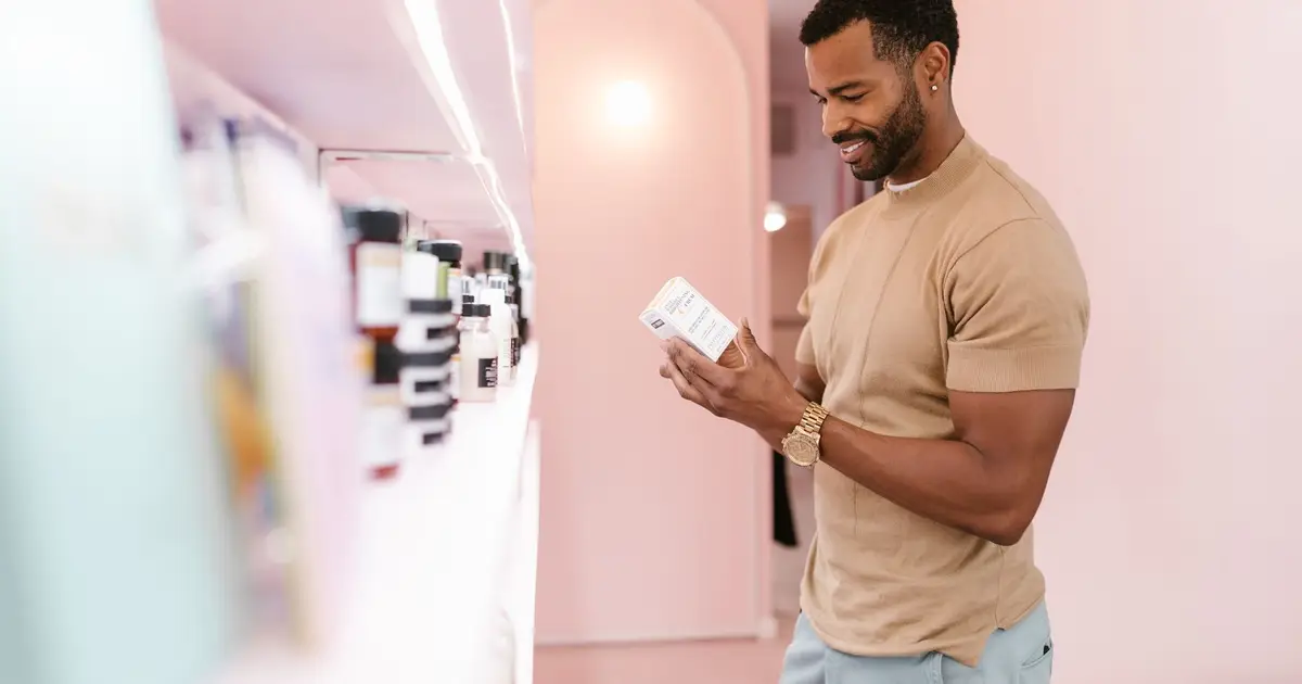 Man examines skincare product label in a modern, well-lit store