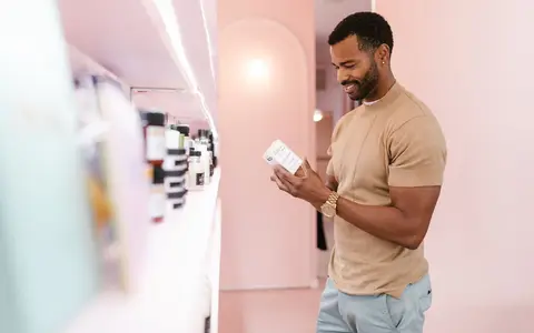 Man examines skincare product label in a modern, well-lit store