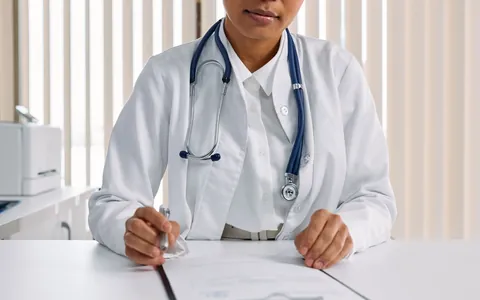A doctor in a white coat writing notes at a desk