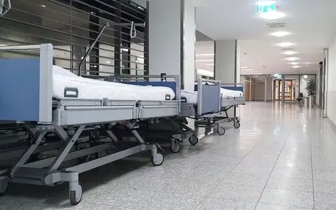 Quiet hospital hallway with neatly arranged empty medical beds under bright ceiling lights