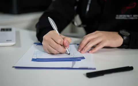 A clinician writing a prescription on paper in a clinic
