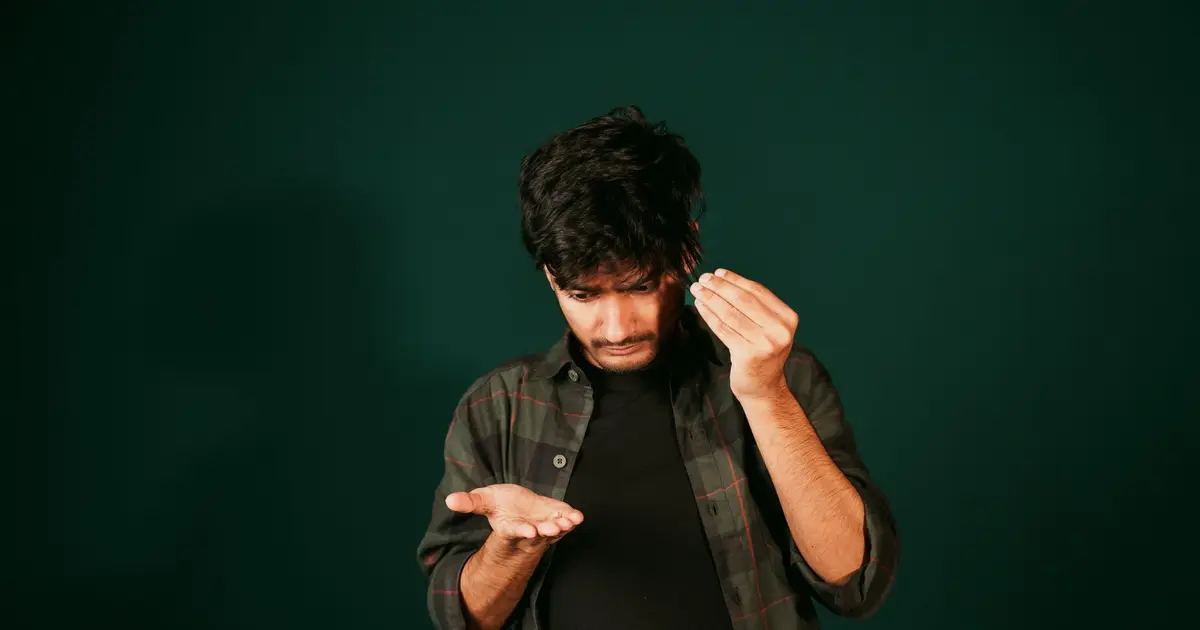 A young man examining hair loss indoors, reflecting self-care concerns