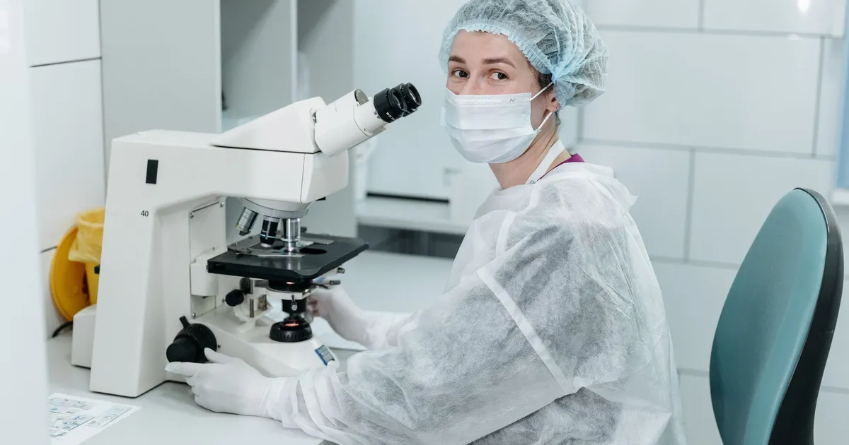 A scientist using a microscope in a sterile laboratory