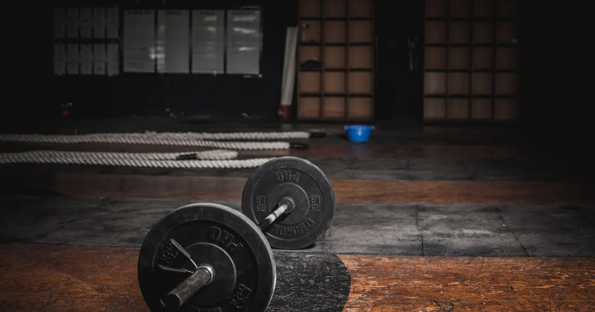 A lone barbell resting in an empty, dimly lit gym