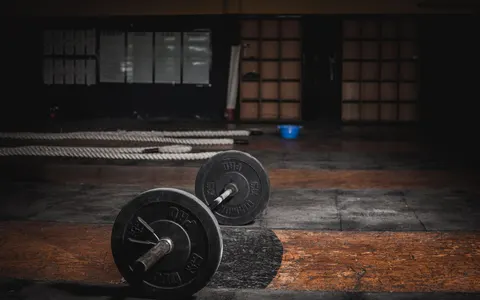 A lone barbell resting in an empty, dimly lit gym