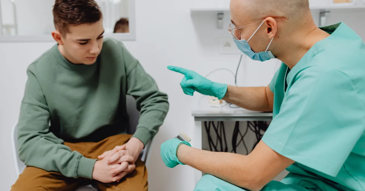 A clinician talking with an adolescent patient during a checkup
