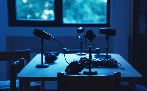 Microphones and headphones on a table in a dimly lit podcast studio