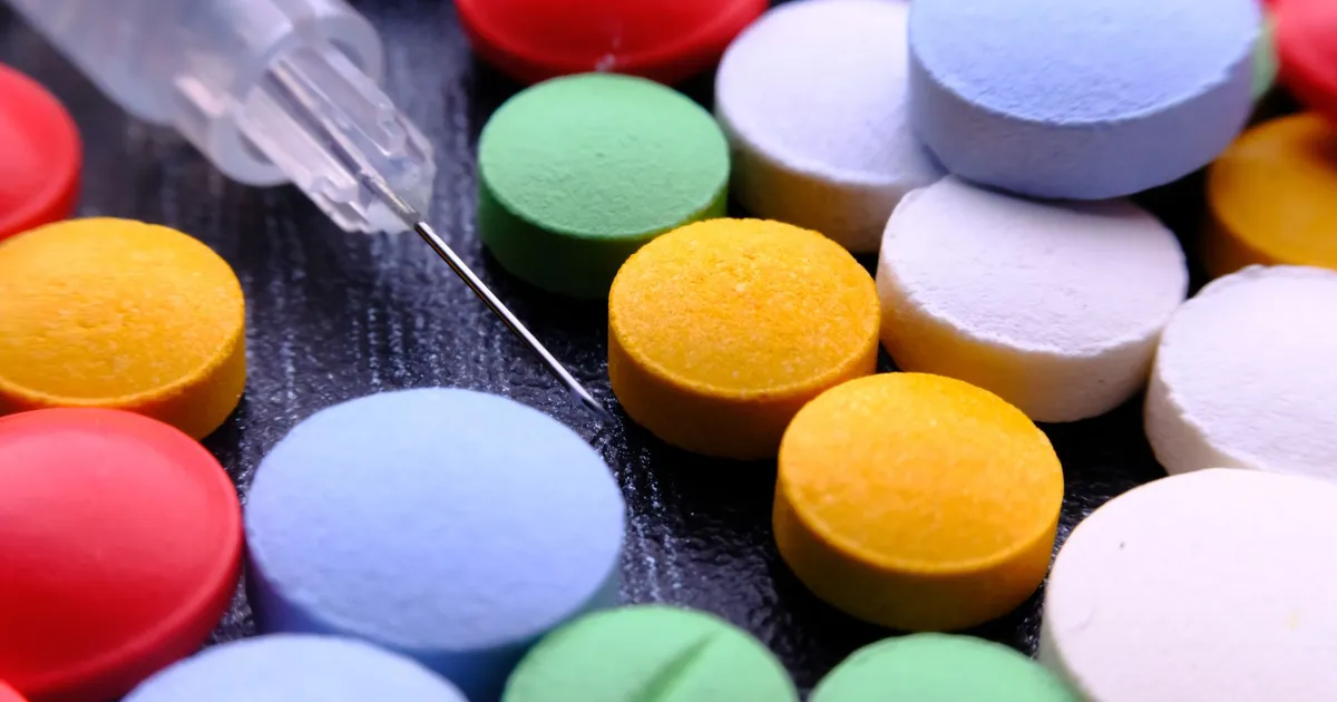 Assorted pills next to a syringe