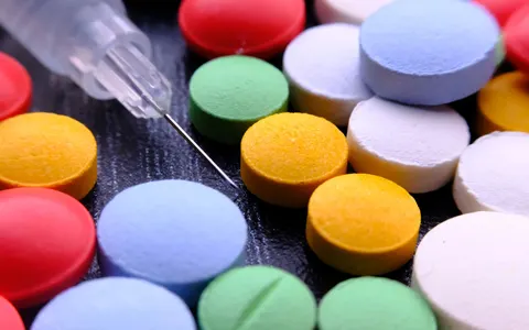 Assorted pills next to a syringe