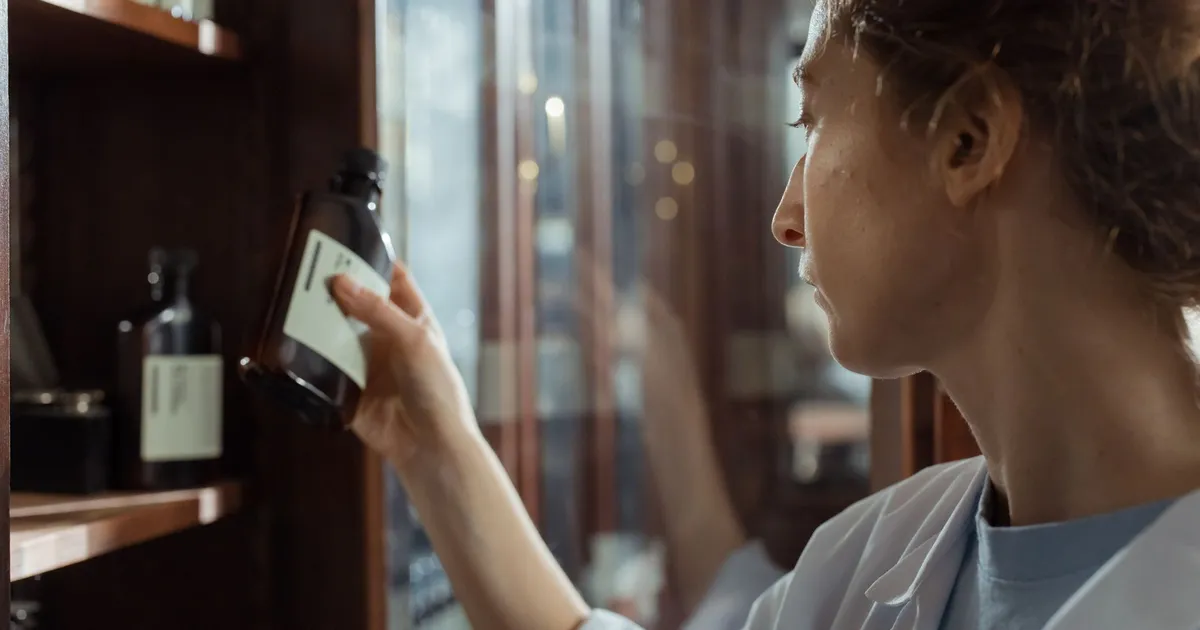 A pharmacist selecting a medicine bottle from a pharmacy shelf