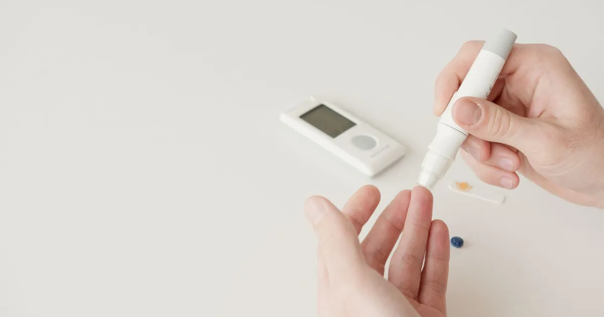 Hands using a lancet pen and a glucometer to test blood sugar
