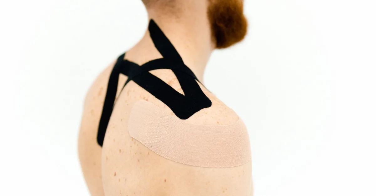 Black kinesiology tape applied to a person's shoulder