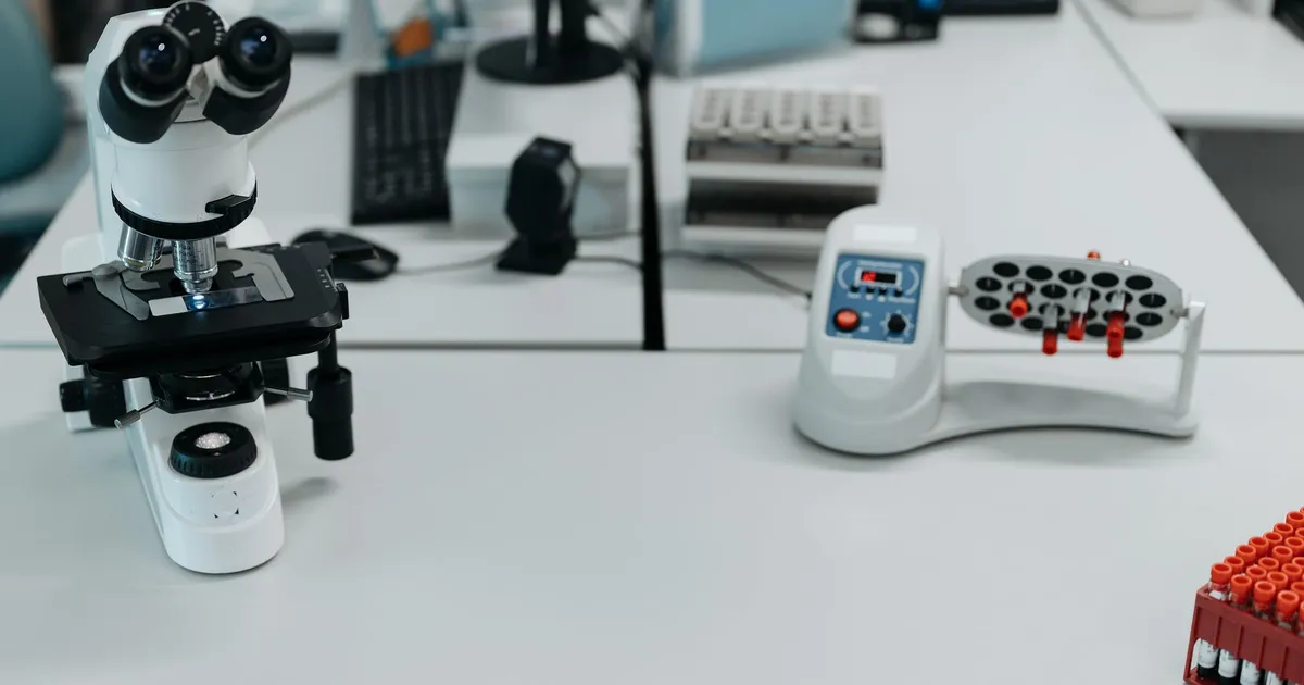 A laboratory desk with a microscope and blood-sample vials