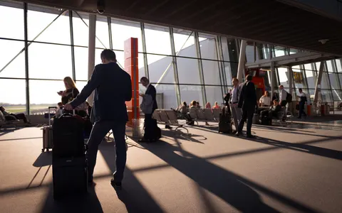 Travellers with carry-on luggage in a busy airport terminal