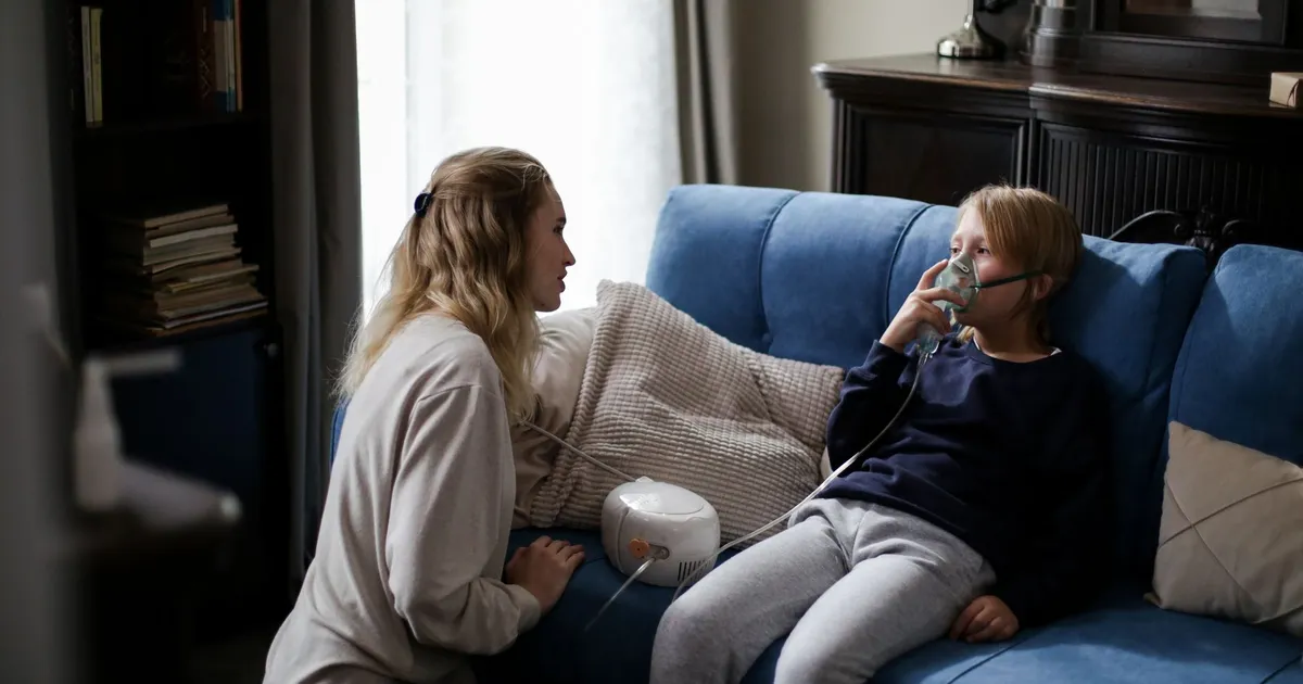 A parent helping a child use a nebulizer at home
