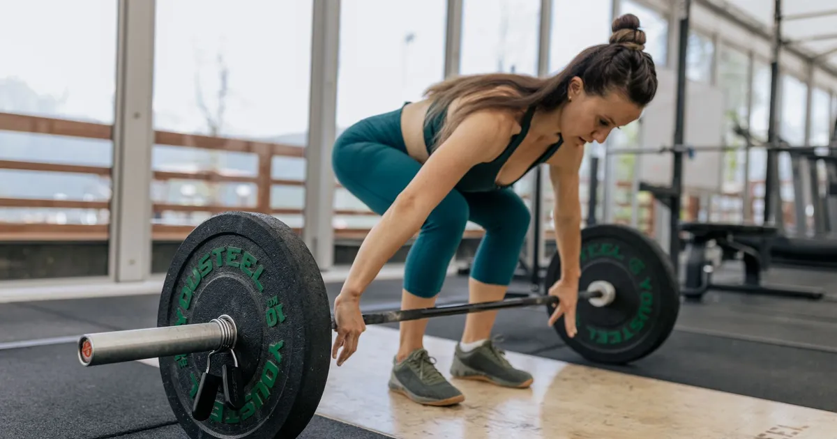 A woman preparing to lift a barbell in a gym
